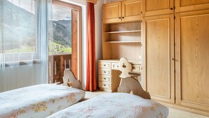 Un dormitorio con dos camas, armario de madera y vistas a las montañas.