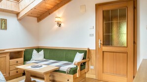 Una habitación acogedora con un banco de madera, una mesa y una puerta con paneles de vidrio esmerilado.