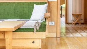 Una cama de madera con colchón verde, almohada blanca y una mesita de noche de madera.