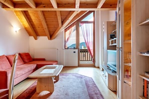 A cozy living room with a red sofa, a wooden coffee table, and a TV on a wooden cabinet.