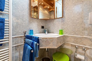 A bathroom with a sink, mirror, towel rack, and green toilet.