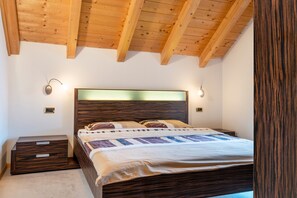 Een slaapkamer met een houten plafond, een bed met hoofdeinde, nachtkastjes en wandlampen.