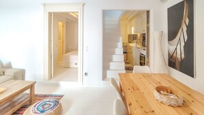 Un intérieur moderne avec une table à manger en bois, un canapé blanc et un escalier menant à un niveau supérieur.
