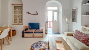 Un salon avec un téléviseur, des meubles en bois, un tapis coloré et un canapé blanc.