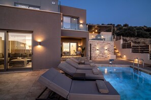 Ein moderner Poolbereich im Freien mit Liegestühlen, einer Steinwand und einer Treppe, die zu einer zweiten Etage führt.