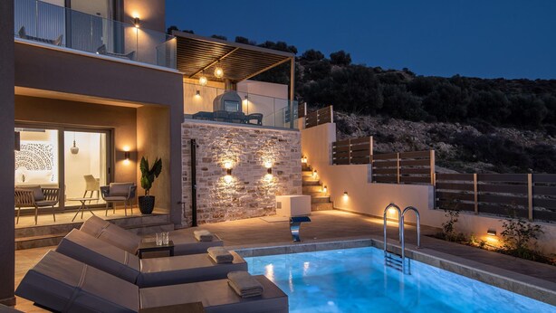 A modern outdoor pool area with lounge chairs, a barbecue grill, and a stone wall. - Villa Paradise 2 in Kalamaki (Faistos)