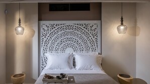 A neatly made bed with a decorative headboard, two hanging lamps, and a wooden tray with fruits and cups on the bedside table. - Villa Paradise 2 in Kalamaki (Faistos)