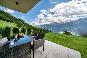 A patio with wicker furniture, a glass table, and a view of mountains. - Holiday Apartment 'Paflur Lodges Lärchenduft' with Mountain View, Garden & Wi-Fi (Lasa)