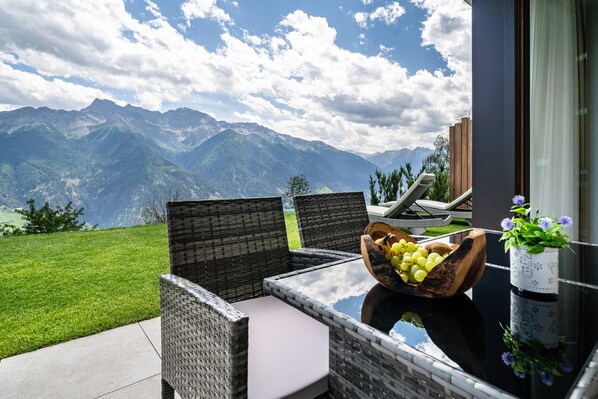 A balcony with wicker furniture, a fruit bowl, and a potted plant.