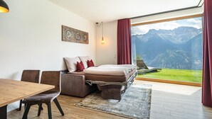 A modern bedroom with a bed, a wooden dining table, and a view of mountains. - Holiday Apartment "Paflur Lodges Abendrot" with Mountain View, Private Terrace & Wi-Fi (Lasa)