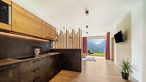 A modern kitchen with wooden cabinets, a built-in oven, and a large window offering a mountain view. - Holiday Apartment "Paflur Lodges Abendrot" with Mountain View, Private Terrace & Wi-Fi (Lasa)