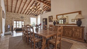 Un coin repas avec une table et des chaises en bois, un mur en pierre et un lustre.