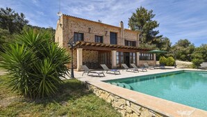 Un bâtiment en pierre doté d’une piscine, d’un espace extérieur aménagé et d’une pergola.