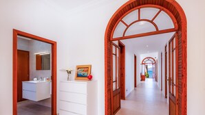 A hallway with a wooden door frame, a white dresser, and a bathroom with a mirror and sink. - Villa "Cas Siulet" with Sea View, 2 Private Terraces & Wi-Fi (Alcudia)
