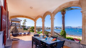 A terrace with a table set for breakfast, overlooking a beach and the sea. - Villa "Cas Siulet" with Sea View, 2 Private Terraces & Wi-Fi (Alcudia)