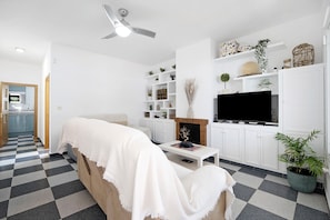 Un salon moderne avec un canapé, un téléviseur à écran plat, une cheminée et un sol à carreaux.