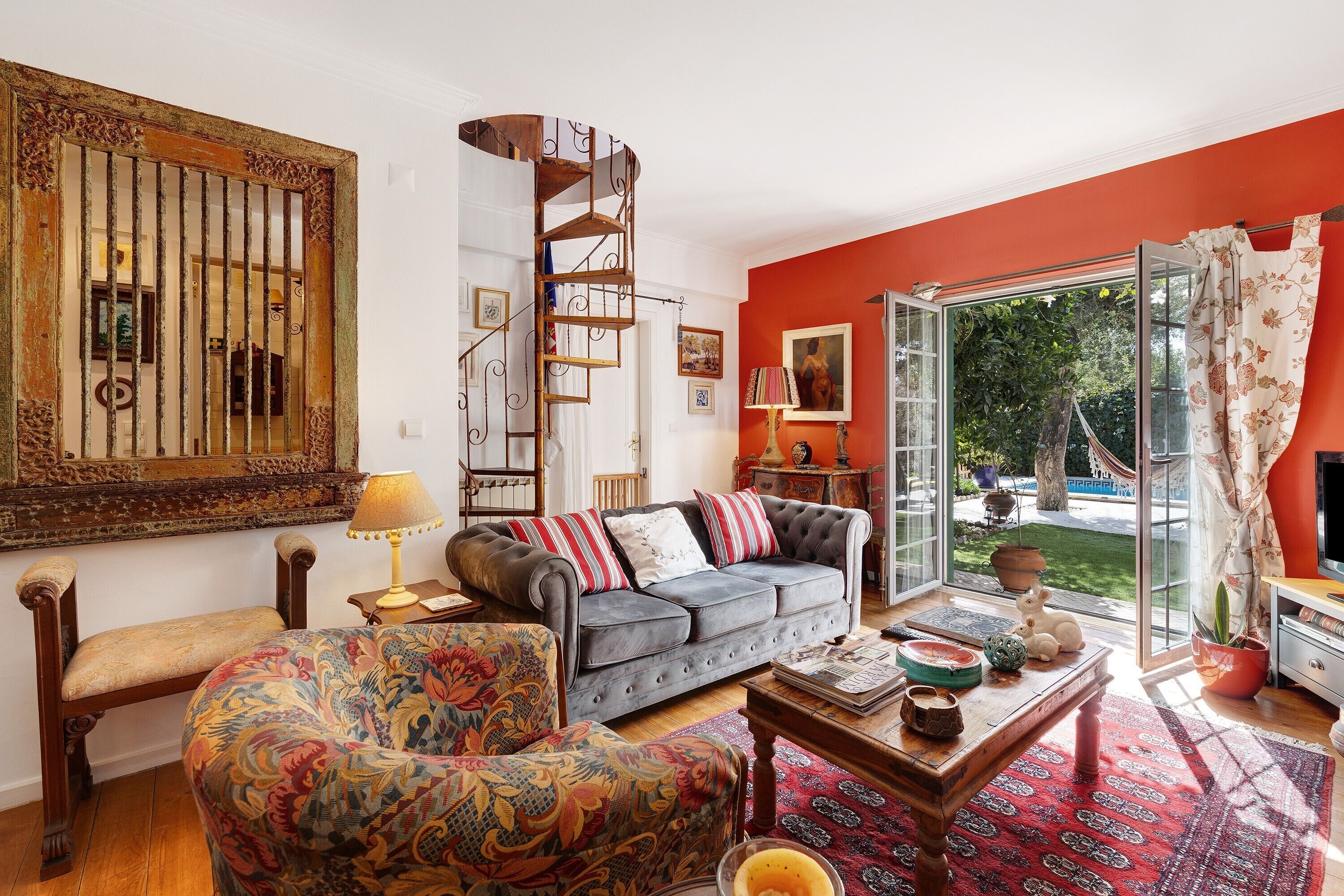 A living room with a sofa, armchair, coffee table, and a spiral staircase.