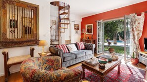 A living room with a sofa, armchair, coffee table, and a spiral staircase. - Villa 'Little Paradise 25 Min From Lisbon' with Private Pool, Private Terrace and Wi-Fi (Azeitão)