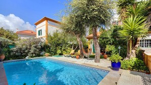 A swimming pool surrounded by lush greenery and a building with a tiled roof. - Villa 'Little Paradise 25 Min From Lisbon' with Private Pool, Private Terrace and Wi-Fi (Azeitão)