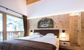 Quarto com cama, cabeceira, quadro na parede e janela com cortinas.