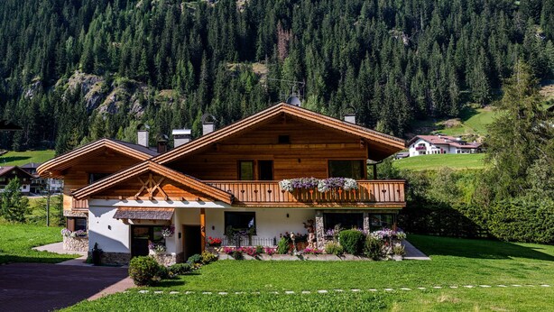 A wooden chalet with a balcony, surrounded by a well-maintained garden and a mountainous backdrop. - Holiday Apartment "Piciulei Pitl" with Mountain View, Garden, and Wi-Fi (Selva di val gardena)