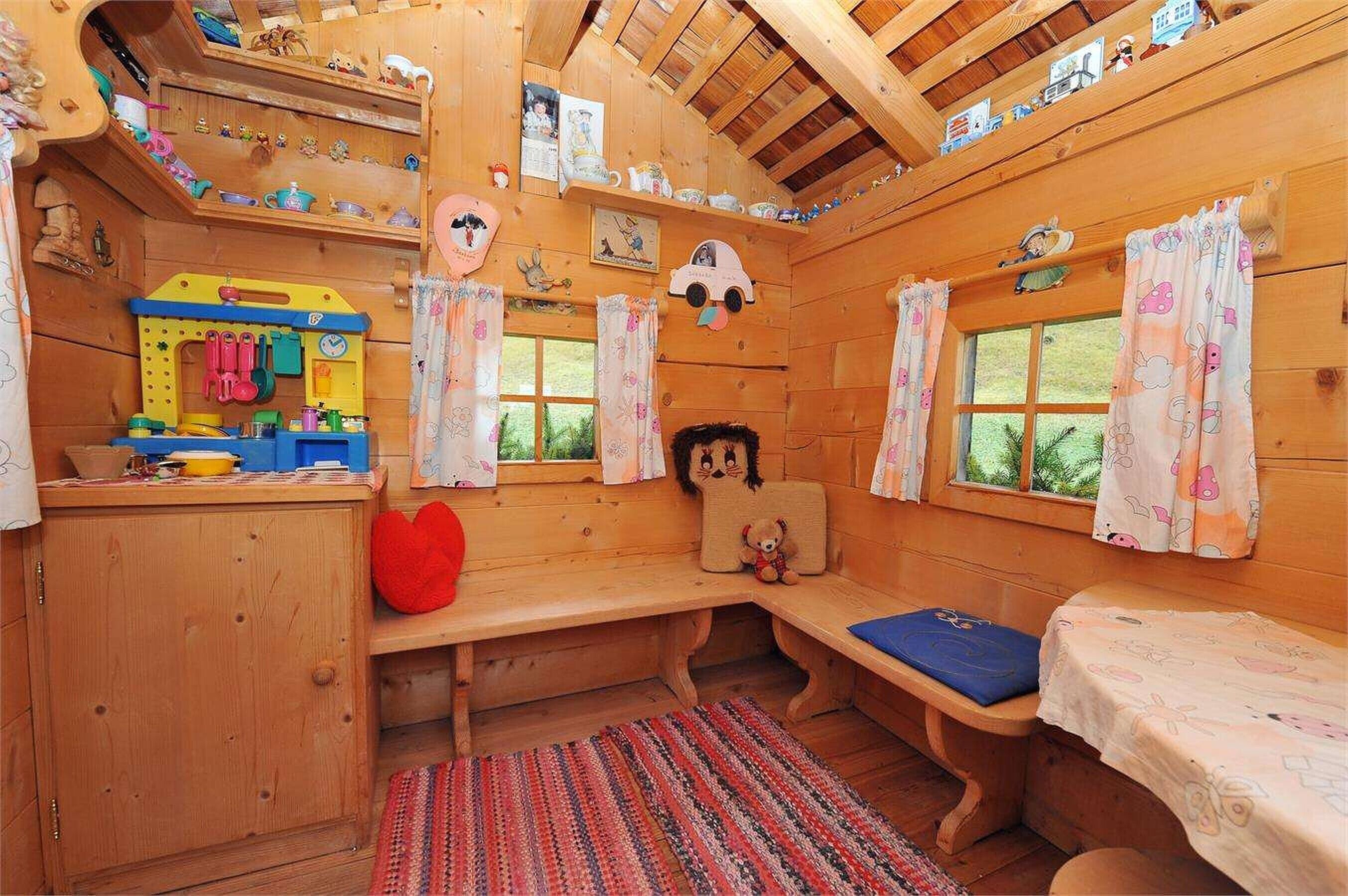 Una cabana acollidora amb parets de fusta, una zona de jocs i una panxa.