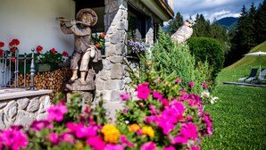 A building with stone walls, a statue of a person playing a flute, and another statue of an owl. - Holiday Apartment "Piciulei Pitl" with Mountain View, Garden, and Wi-Fi (Selva di val gardena)