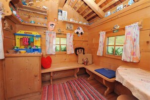 Una cabaña acogedora con paredes de madera, un espacio de juegos y un banco.