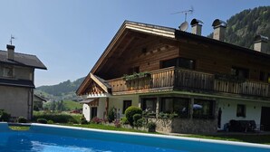 A swimming pool with a wooden building in the background. - Apartment "Piciulei Grant" with Mountain View, Garden, and Wi-Fi (Selva di val gardena)