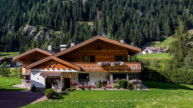 A wooden chalet with a balcony, surrounded by a well-maintained garden and a mountainous backdrop. - Apartment "Piciulei Grant" with Mountain View, Garden, and Wi-Fi (Selva di val gardena)