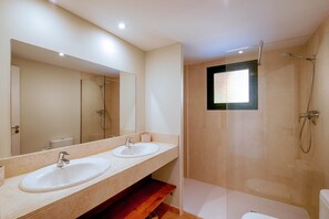 Un baño moderno con dos lavamanos, ducha e inodoro.