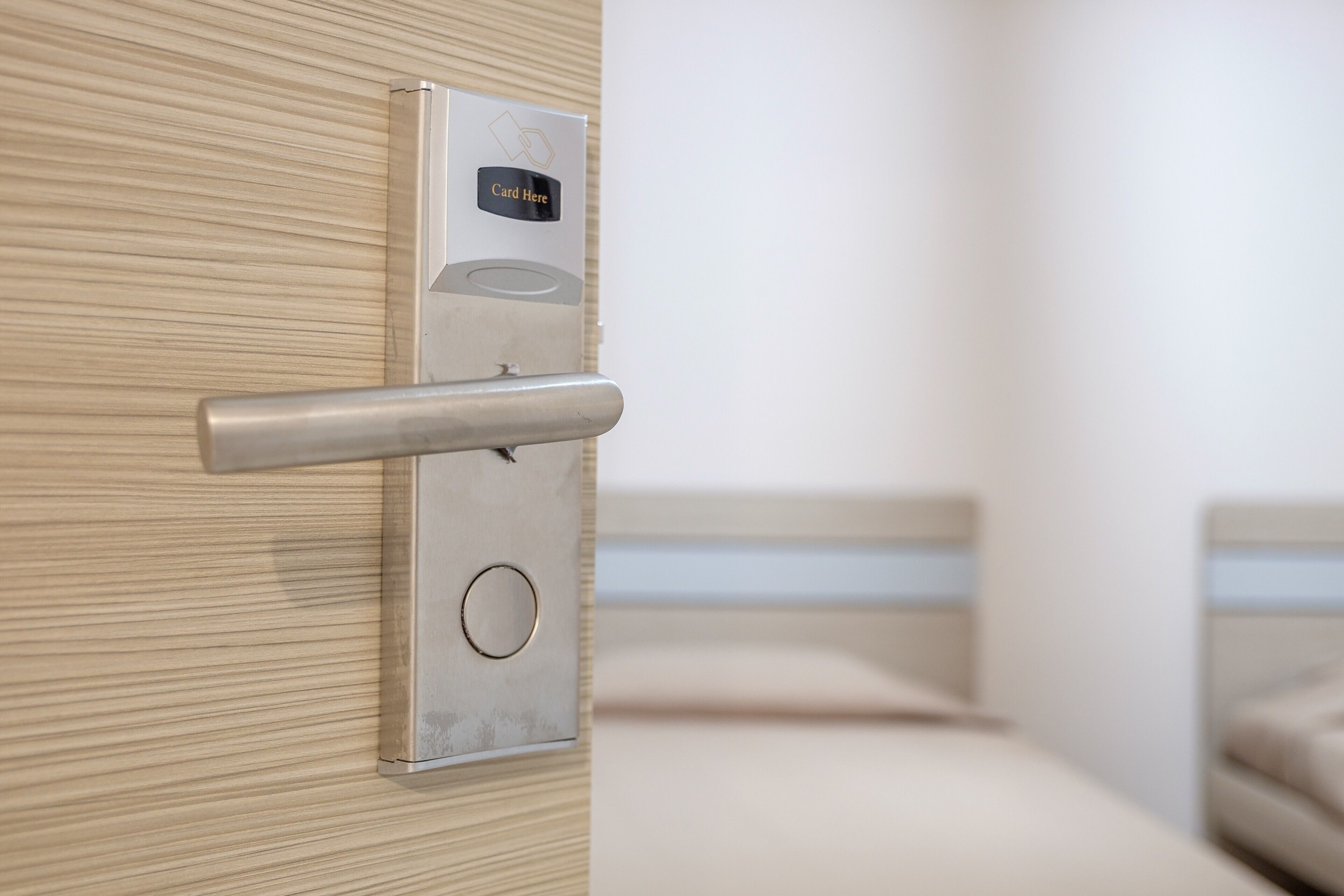 A modern door with a card reader, a metallic handle, and a circular lock mechanism.