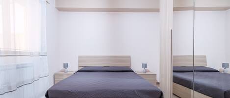 Une chambre moderne avec un grand lit, des tables de chevet, un miroir et un luminaire au plafond.