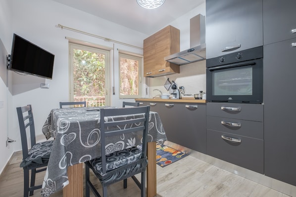 Une cuisine moderne avec une table à manger, des chaises, un téléviseur et une grande fenêtre.
