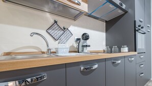 Una cocina moderna con un lavamanos de acero inoxidable, una campana extractora empotrada y armarios grises.