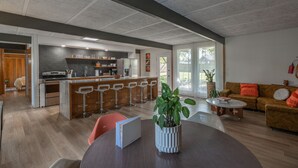 A modern kitchen with a central island, bar stools, and a dining area with a table and chairs. - Retro Vibes | Mid-Century Gem in Springfield (Springfield)