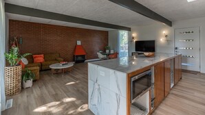 A modern living room with a brick wall, a sofa, a coffee table, and a TV. - Retro Vibes | Mid-Century Gem in Springfield (Springfield)
