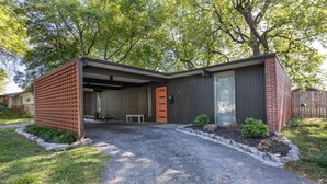 A modern house with a covered garage, a brick exterior, and a gravel driveway. - Retro Vibes | Mid-Century Gem in Springfield (Springfield)