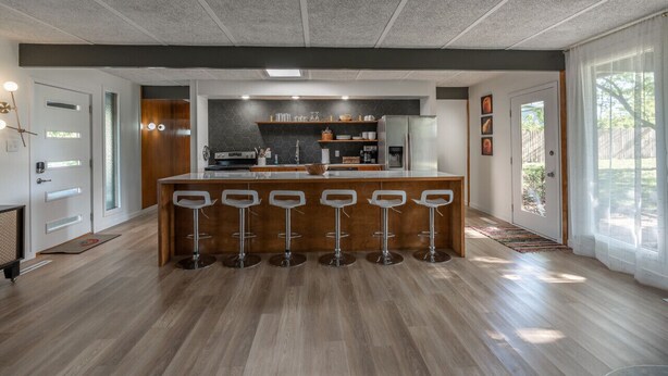 A modern kitchen with a central island, bar stools, and a large window. - Retro Vibes | Mid-Century Gem in Springfield (Springfield)