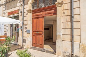 A building entrance with a wooden door, a sign above the door, and a number '68' on the wall.
