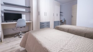 Un dormitorio con una cama, un escritorio con computadora y un armario.