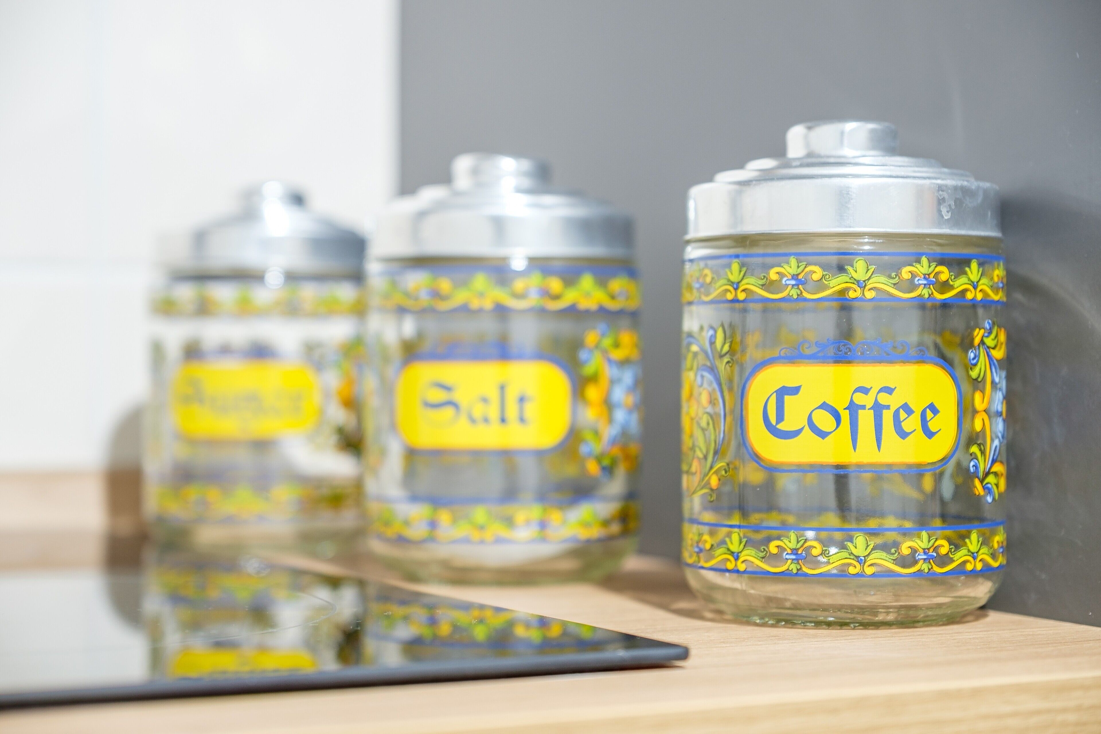 Three glass containers with labels on a reflective surface.
