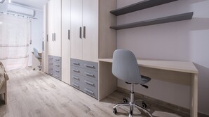 Un dormitorio con cama, escritorio, silla y armario empotrado con cajones.