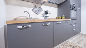 Una cocina moderna con armarios grises, encimera de madera, horno empotrado y campana extractora de acero inoxidable.