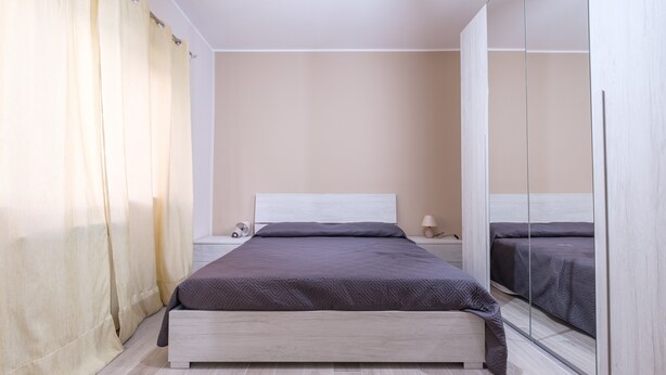 Une chambre à coucher avec un lit, une table de chevet et un meuble-miroir.