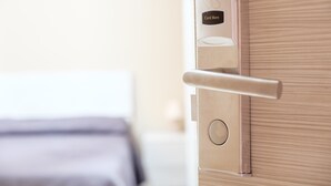 Une porte de chambre d’hôtel équipée d’un lecteur de carte, d’un trou de serrure et d’une poignée.