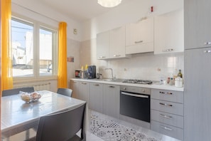 A modern kitchen with a dining area, featuring a stove, sink, and cabinets. - Holiday Apartment "Contessa Vacanze Byron" with Mountain View, 2 Balconies and Wi-Fi (Contessa Entellina)