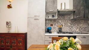 Eine Küche mit einem Holztisch, einem Blumenstrauß und einer Kaffeemaschine.