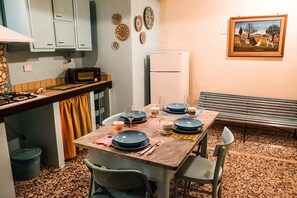 Ruokailutila, jossa on neljälle katettu ruokapöytä, keittiön kaapit, mikroaaltouuni ja jääkaappi.