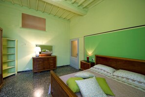 Une chambre à coucher comprenant un lit, des tables de chevet, une armoire, une étagère et une porte.